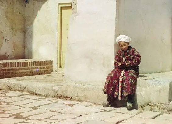Un petit garçon assis dans la cour de la mosquée Tillia-Kari de Samarkand (Ouzbékistan actuel)