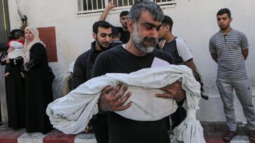 Un palestinien tient le corps de son enfant mort, enveloppé dans un linceul - Photo : Abedelhakim Abu Riash/Al Jazeera
