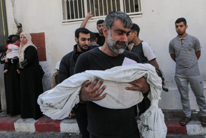 Un palestinien tient le corps de son enfant mort, enveloppé dans un linceul - Photo : Abedelhakim Abu Riash/Al Jazeera